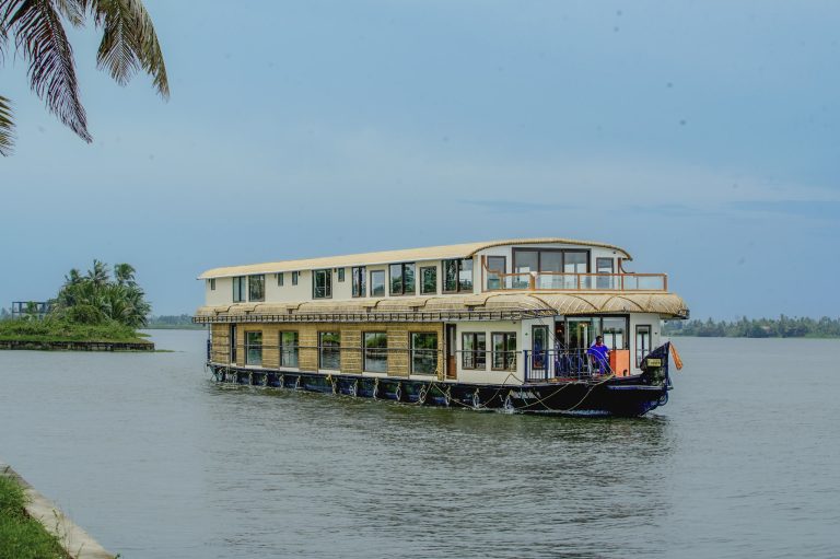 Luxury houseboat cruising through Alleppey backwaters surrounded by palm trees