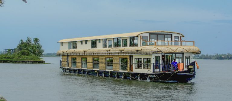 Luxury houseboat cruising through Alleppey backwaters surrounded by palm trees