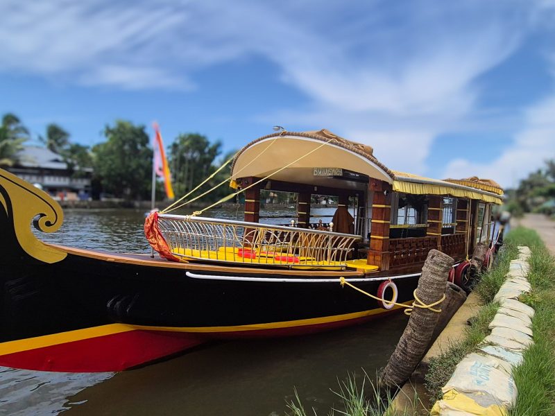 Air-conditioned premium shikara boat docked along the Alleppey backwaters on a sunny day in Kerala, India