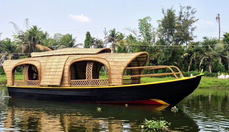 Premium bamboo cane shikara boat floating on a calm Alleppey backwater canal in Kerala